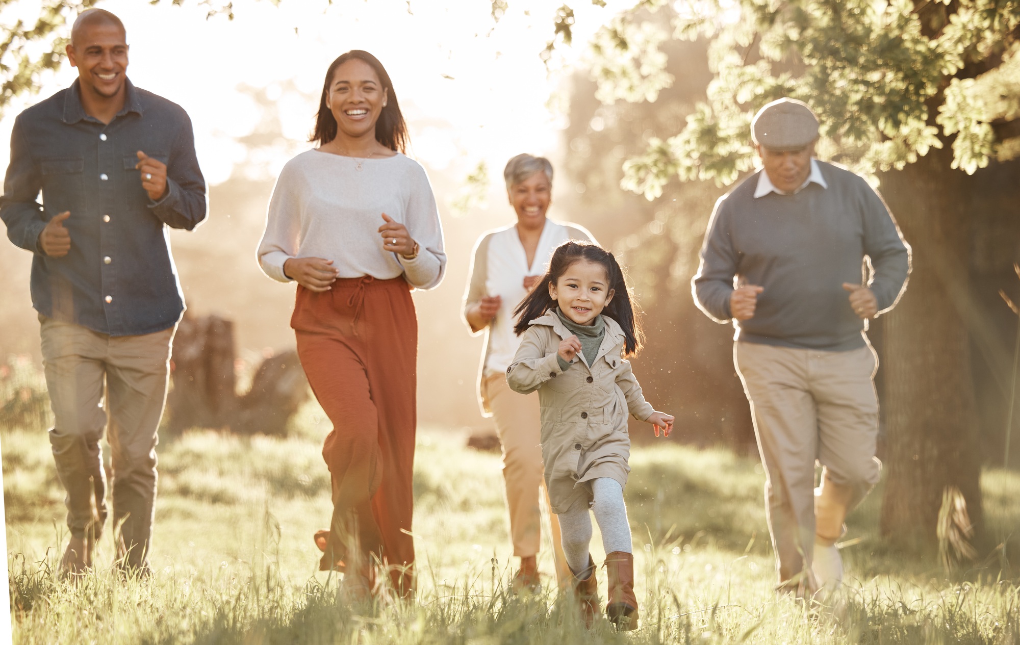 Family, running and parents or grandparents with girl child in park for freedom, adventure or playi