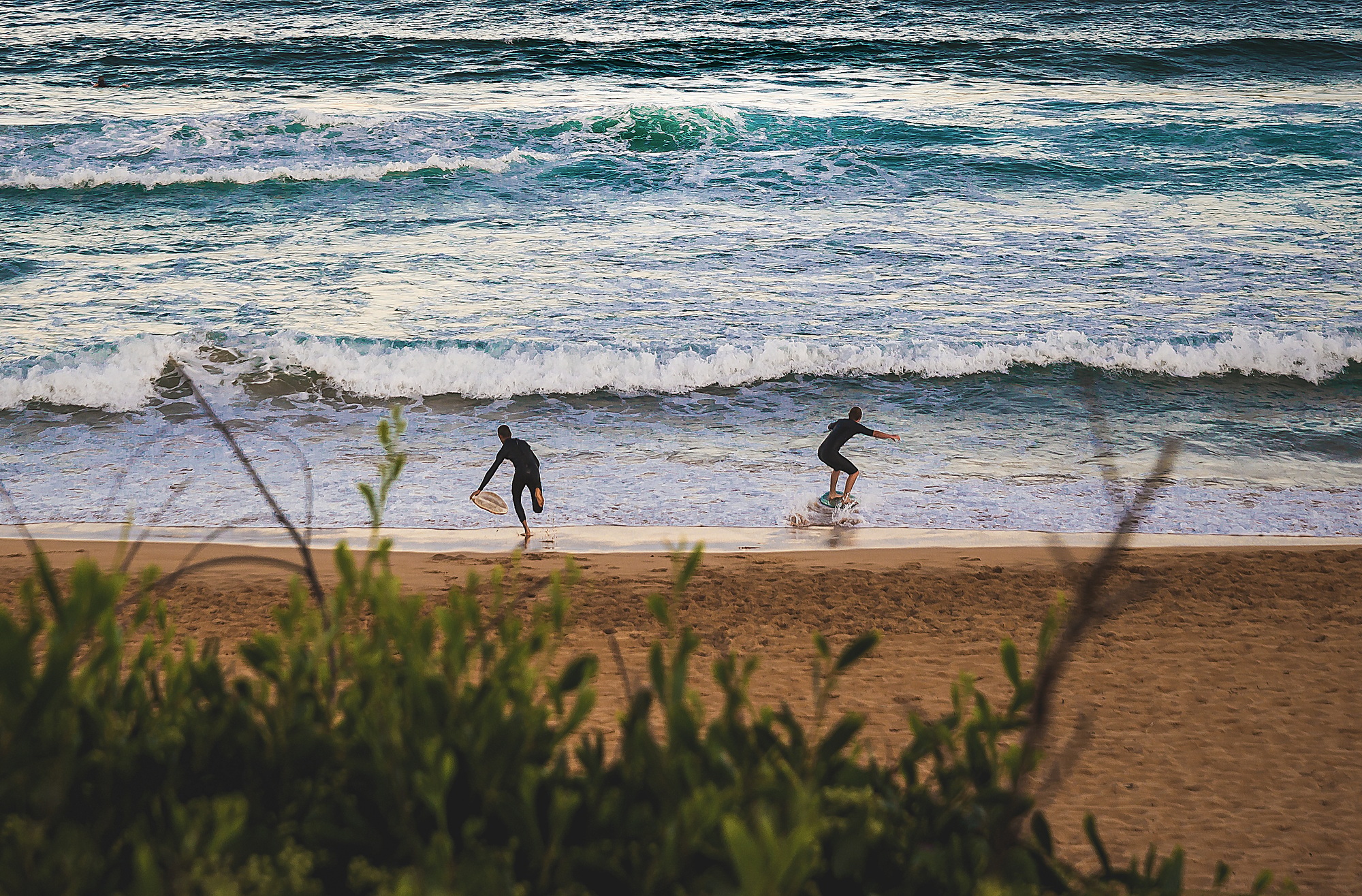 Friends Running Into The Ocean With Their Skimboard. Water Sport. Summer Vacations