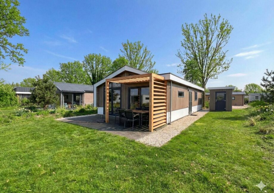 Modernes Ferienhaus mit überdachter Terrasse und großem Garten bei blauem Himmel. - Villa Sunset Beach