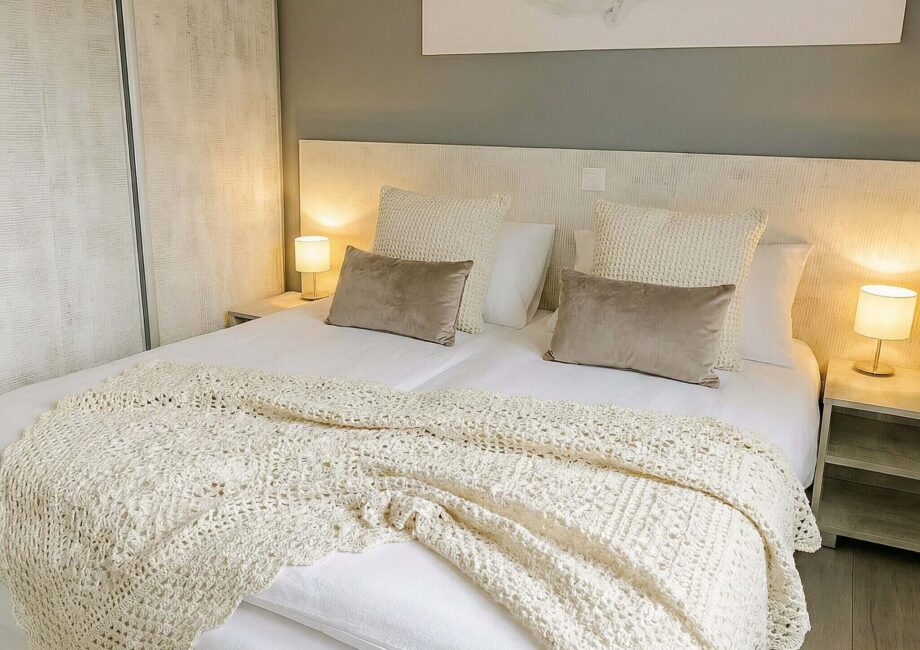 Helles, modernes Schlafzimmer mit Doppelbett, Nachttischen und warmem Licht in neutralen Farben. - Villa Sea Side