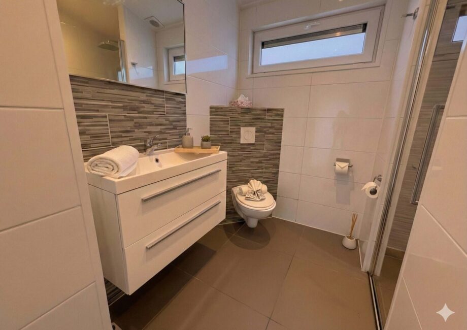 Helles, modernes Badezimmer mit Waschtisch, Spiegel, WC und Glasdusche in der Villa Sea Side.