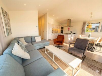 Helles, modernes Wohnzimmer mit Sofa, Sesseln, Esstisch und offener Küche in der Villa Sea Side.