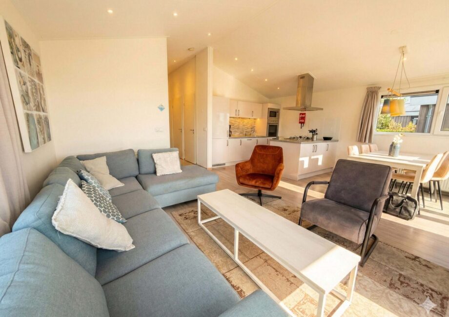 Helles, modernes Wohnzimmer mit Sofa, Sesseln, Esstisch und offener Küche in der Villa Sea Side.