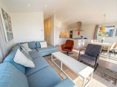 Heller Wohn- und Essbereich mit offener Küche, Sofa, Sesseln und großem Fenster in modernem Ferienhaus. - Villa Sea Side
