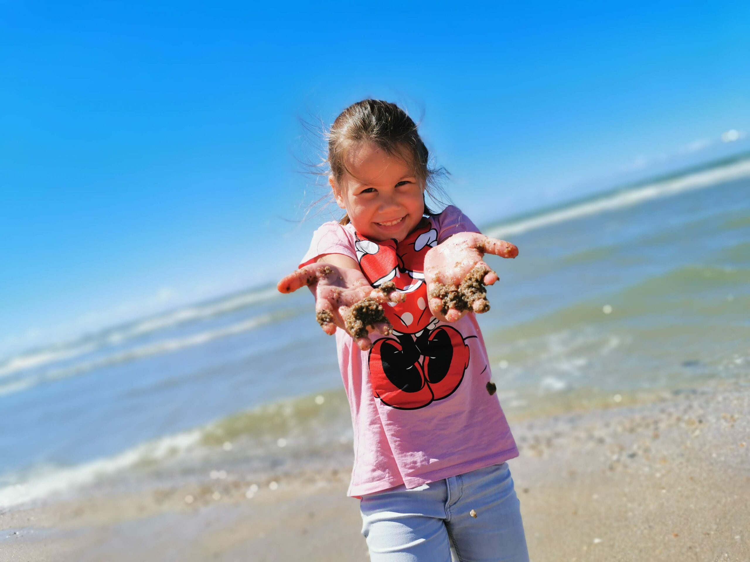 Kind mit sandigen Haenden am Strand - Familienurlaub bei Seashell Retreats